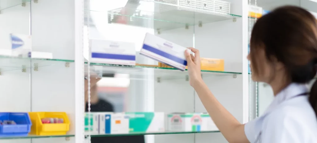 apothekersassistente plaatst een doosje medicijnen in de voorraadkast