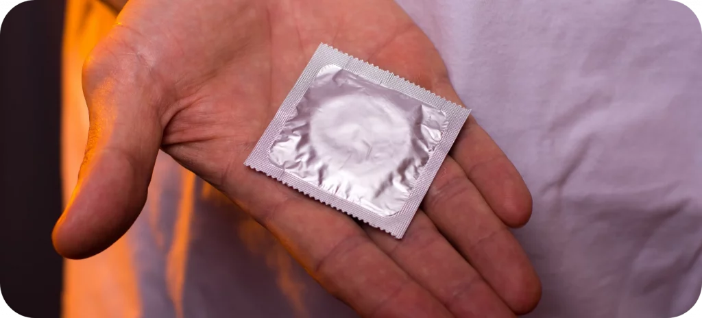 Een afbeelding van een persoon met een condoom in zijn hand in het 'Anticonceptie en hiv-remmers' artikel.