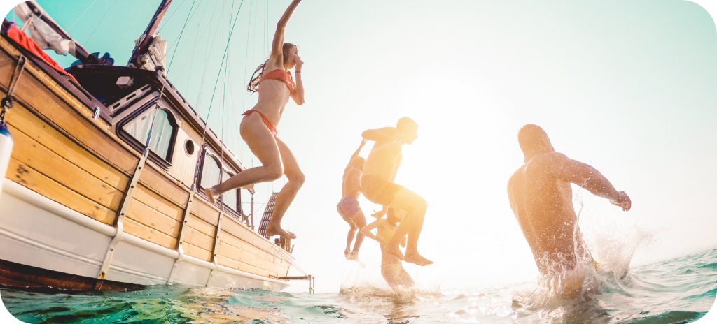 Een afbeelding van jongvolwassenen die tijdens hun vakantie lol hebben en vanuit een boot in de zee springen in het 'Reizen met ADHD-medicatie: Handige tips en adviezen' artikel.
